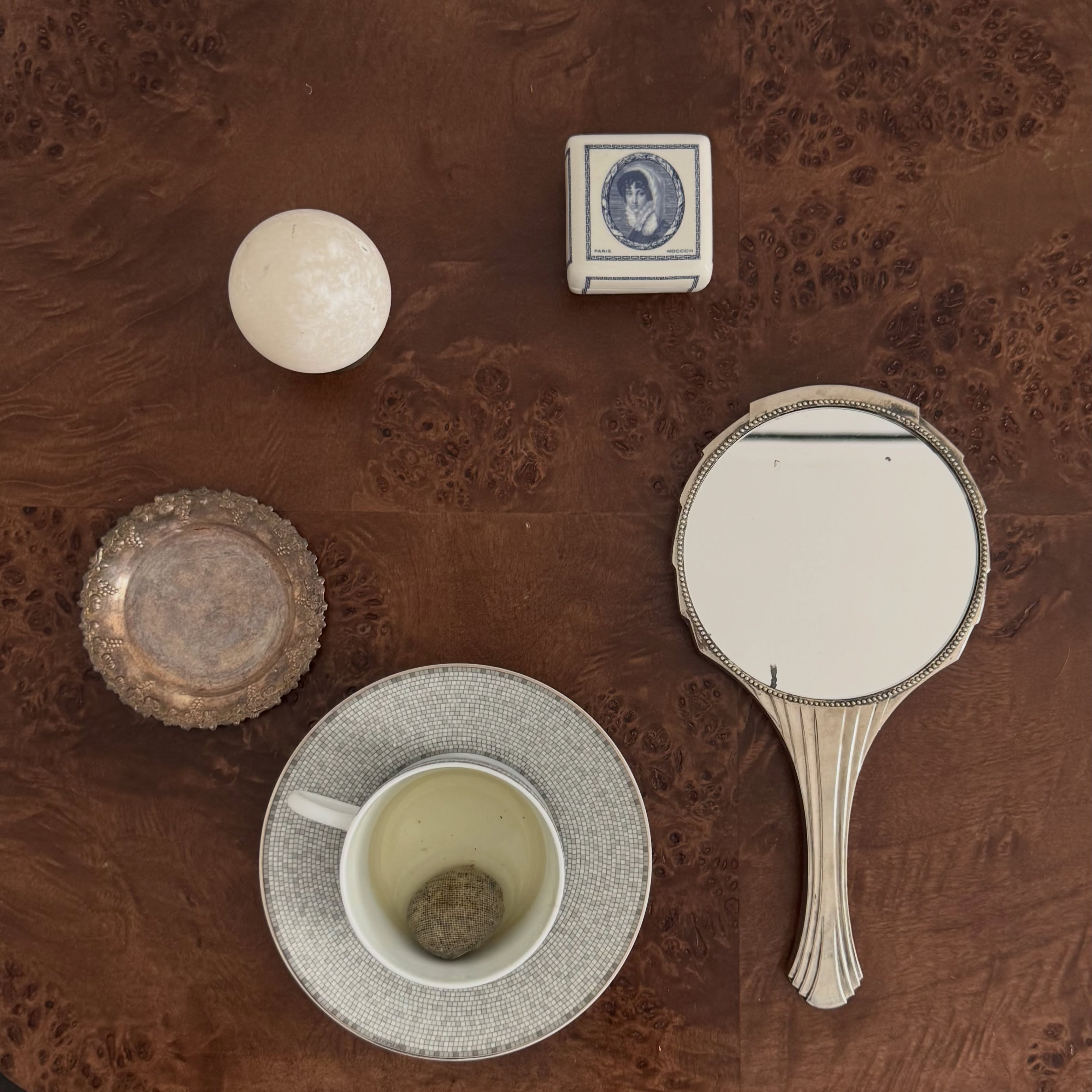 A mirror, tea, and other things placed on a tabletop.