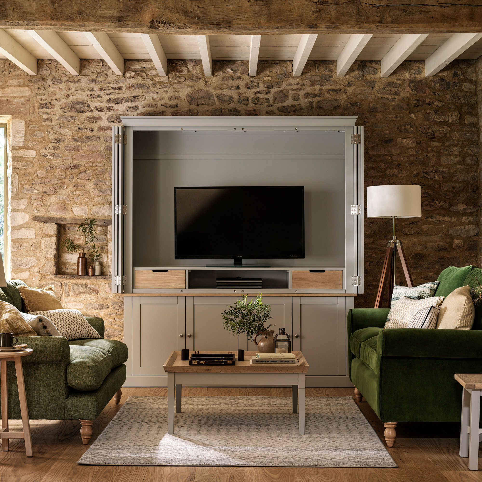 rustic living room with exposed stone wall and green sofas