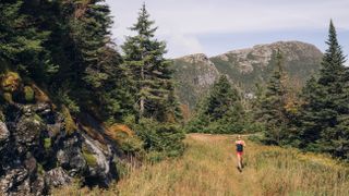 Woman trail running on a rocky ridgeline in New England