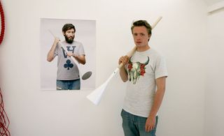 Brynjar Sigurðarson with his ’Tool light’ standing next to a wall portrait of a man holding the tool light