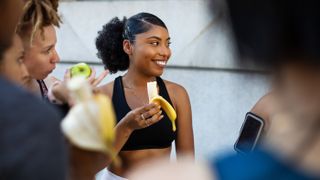 A fit woman is eating a banana after a workout. Bananas can be a helpful snack during exercise.