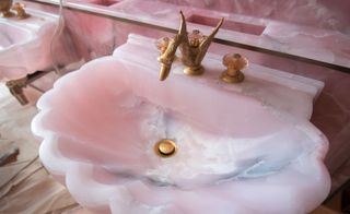 A pink onyx sink inside the ladies powder room, under a ceiling canopy of pink satin flowers