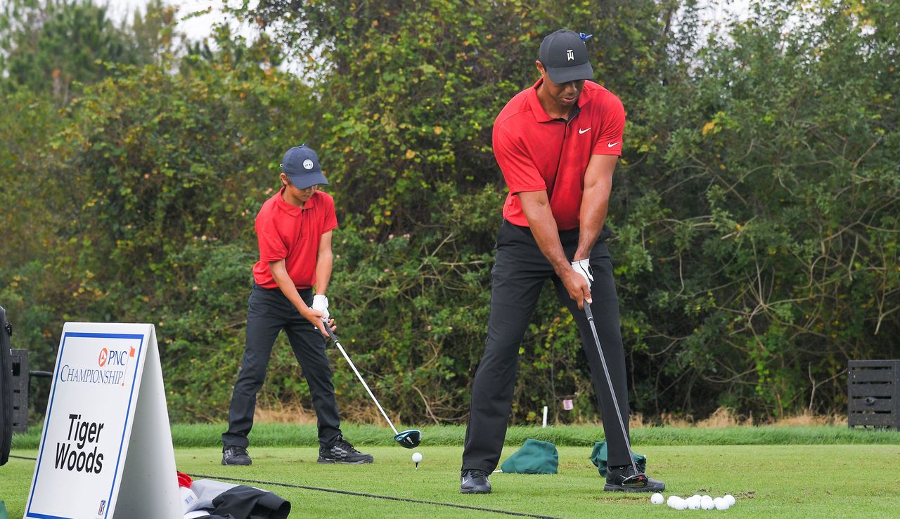 Tiger and Charlie hit golf balls on the driving range