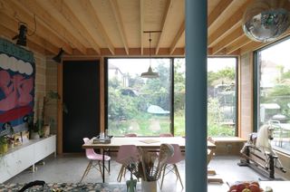 Dining room with dining table, pink chairs and big windows at Forest House