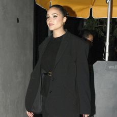 Olivia Culpo wearing a black blazer, black sweater, black stirrup leggings, black heels