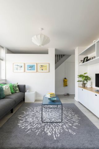 modern white living room with a grey sofa, grey statement rug and colourful art prints