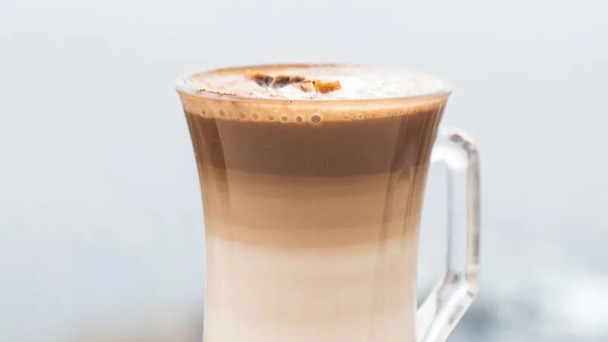 a hot tumbler with striated horizontal layers of espresso and foamed milk