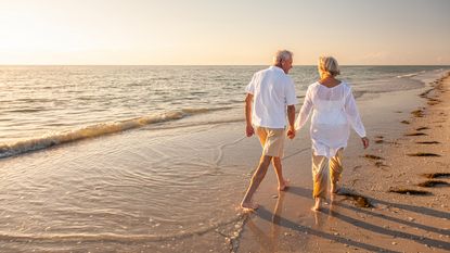 A senior couple is strolling along the beach.