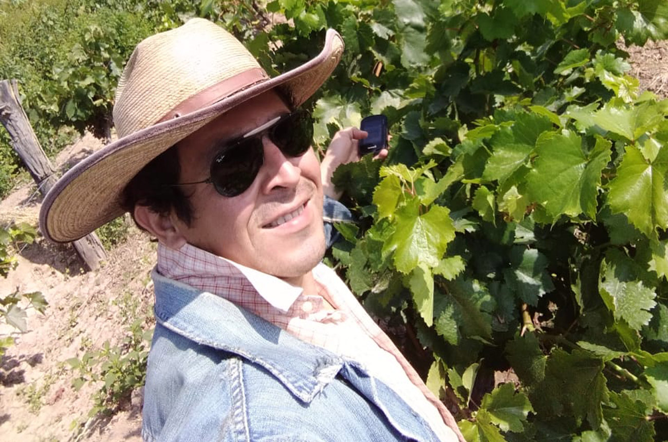 A man in a cowboy hat and sunglasses in a vineyard