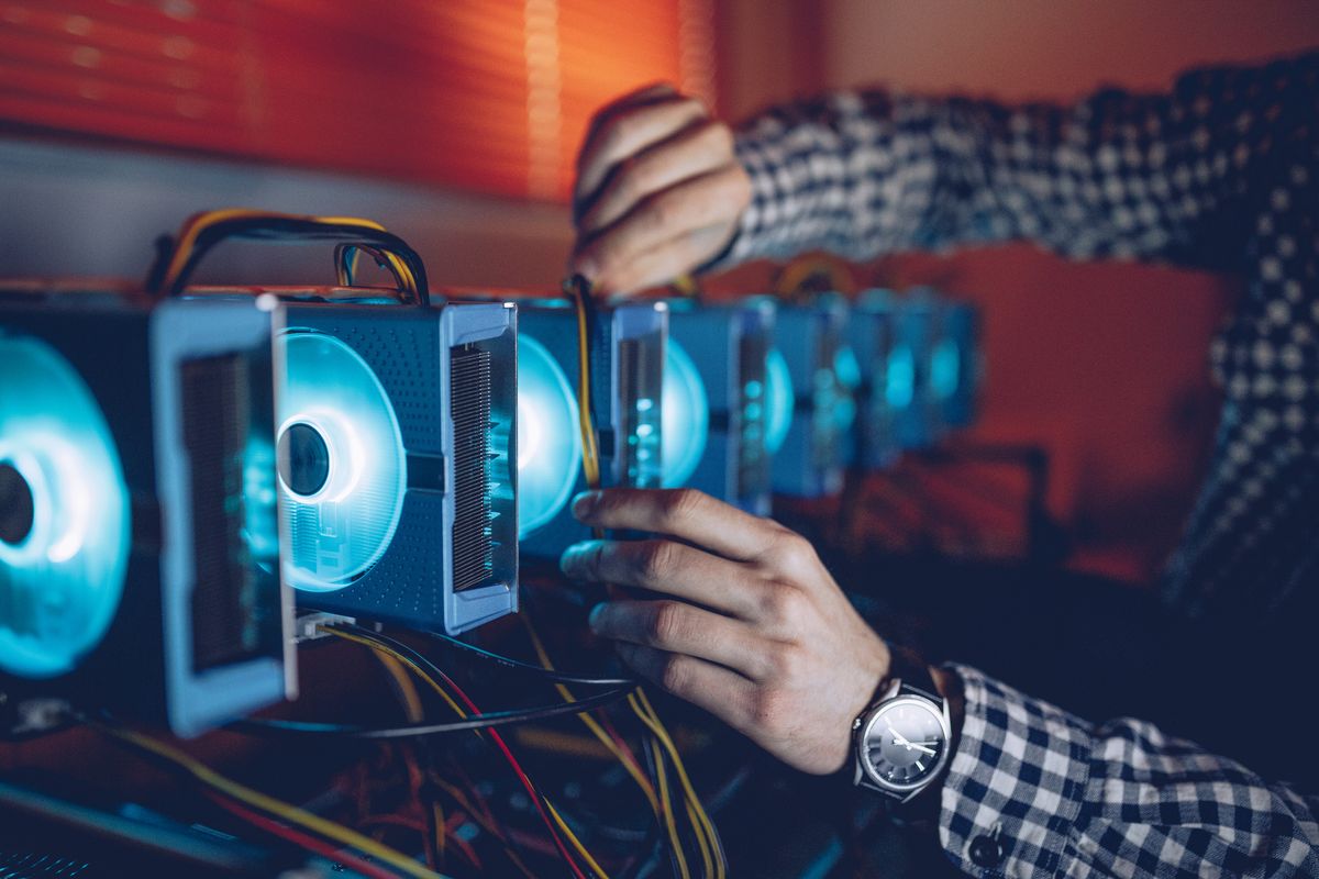 A programmer setting up a cryptocurrency mining rig using a series of connected graphics cards