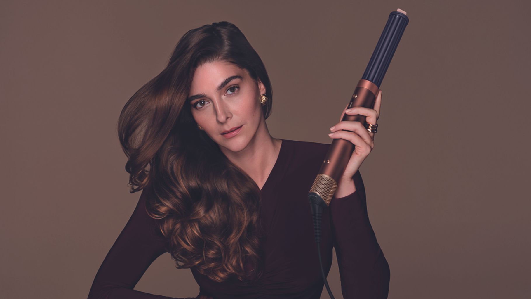 Woman holding Dyson hair styler in Plum and Copper colorway