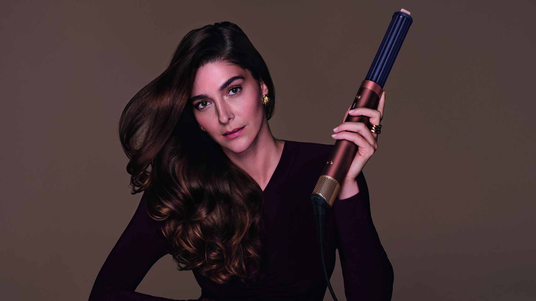 Woman holding Dyson hair styler in Plum and Copper colorway