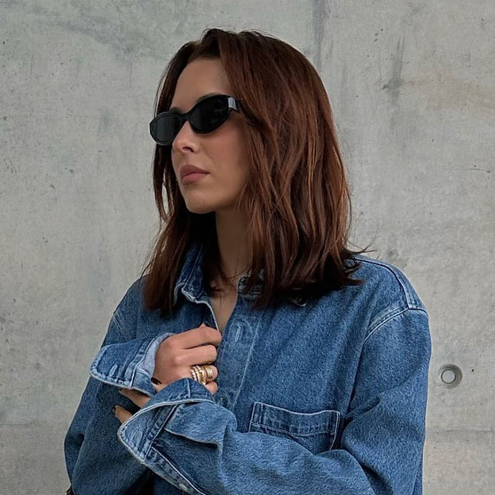 A woman wearing a denim button down shirt and black sunglasses