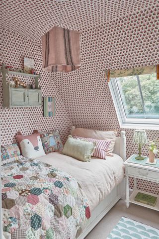 decorative child's room with pink wallpaper all over and patchwork quilt on bed