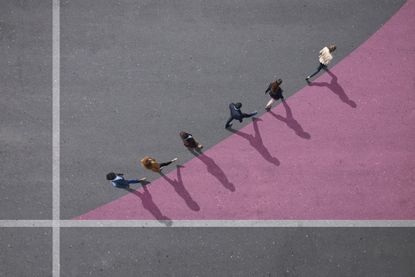 six people walking in single file along the top line of a pink chalked triangle