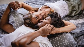 male and female couple laughing and holding hands in bed together
