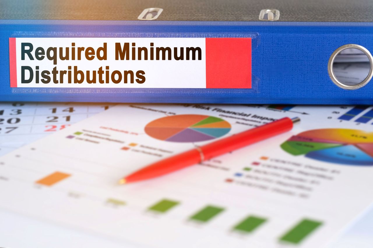 A binder with required minimum distributions written on the side sitting on top of some charts. 