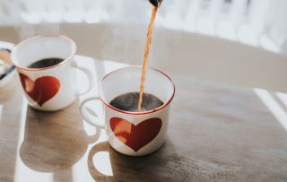 Two heart mugs with coffee in them, which experts say you can drink while pregnant