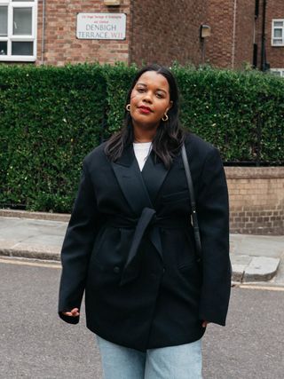 a photo of a woman's work outfit with a tailored black blazer layered over a white t-shirt with jeans