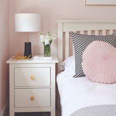 Bedroom with a bed and bedside table against a pink wall