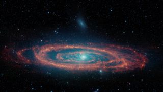 An image of a galaxy against the backdrop of space. It has a blueish center, is seen kind of edge-on and has reddish disks around it.