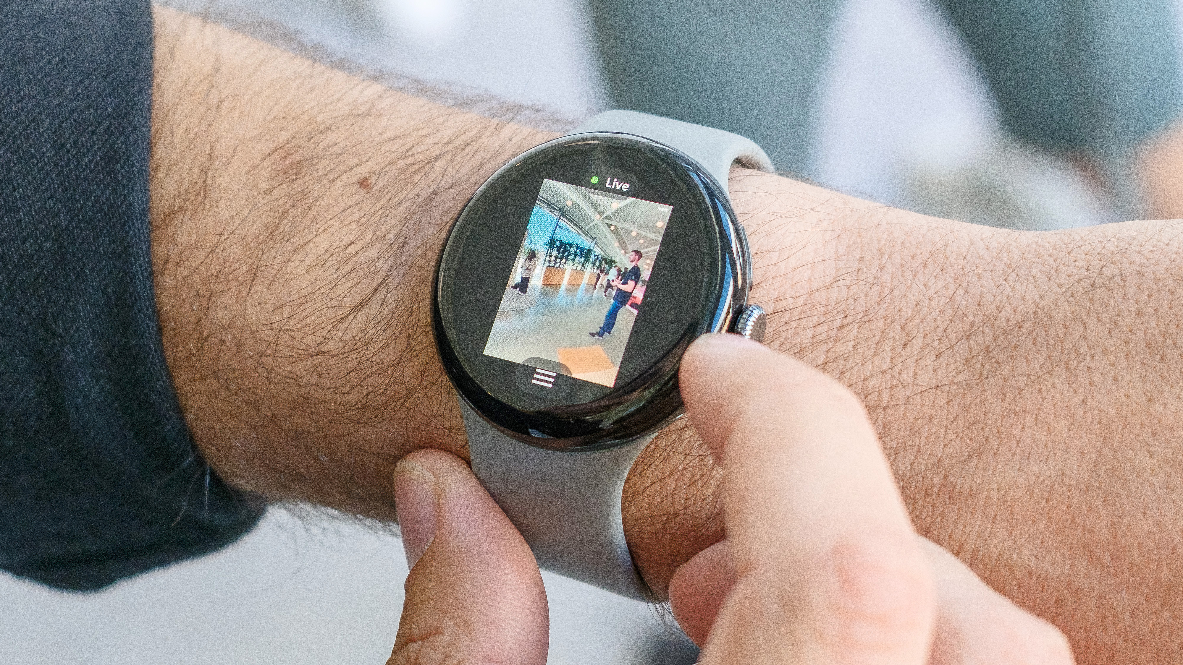 The Google Pixel Watch 3 on a user's wrist shows the live feed from a Nest camera