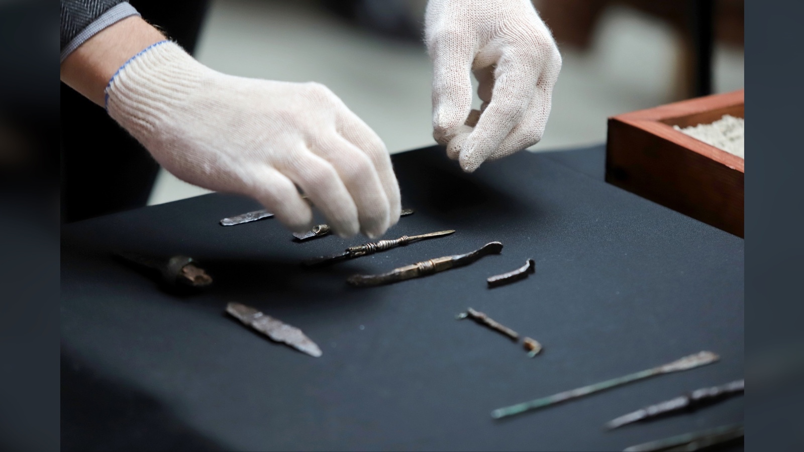 Aquí vemos un par de manos enguantadas manipulando con cuidado los escalpelos de la época romana.