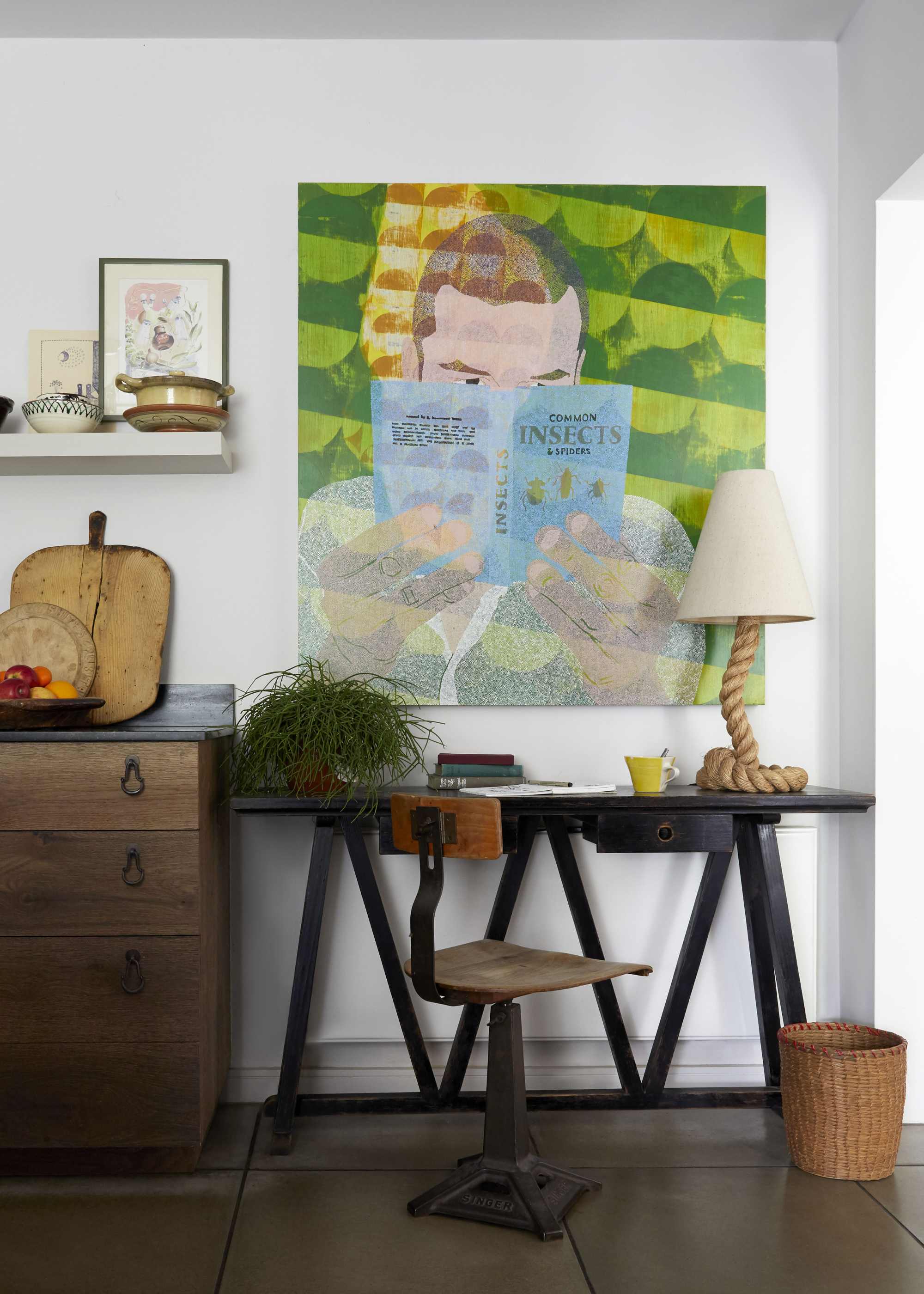 a cool small home office with a green art work above a small black desk with a rope light