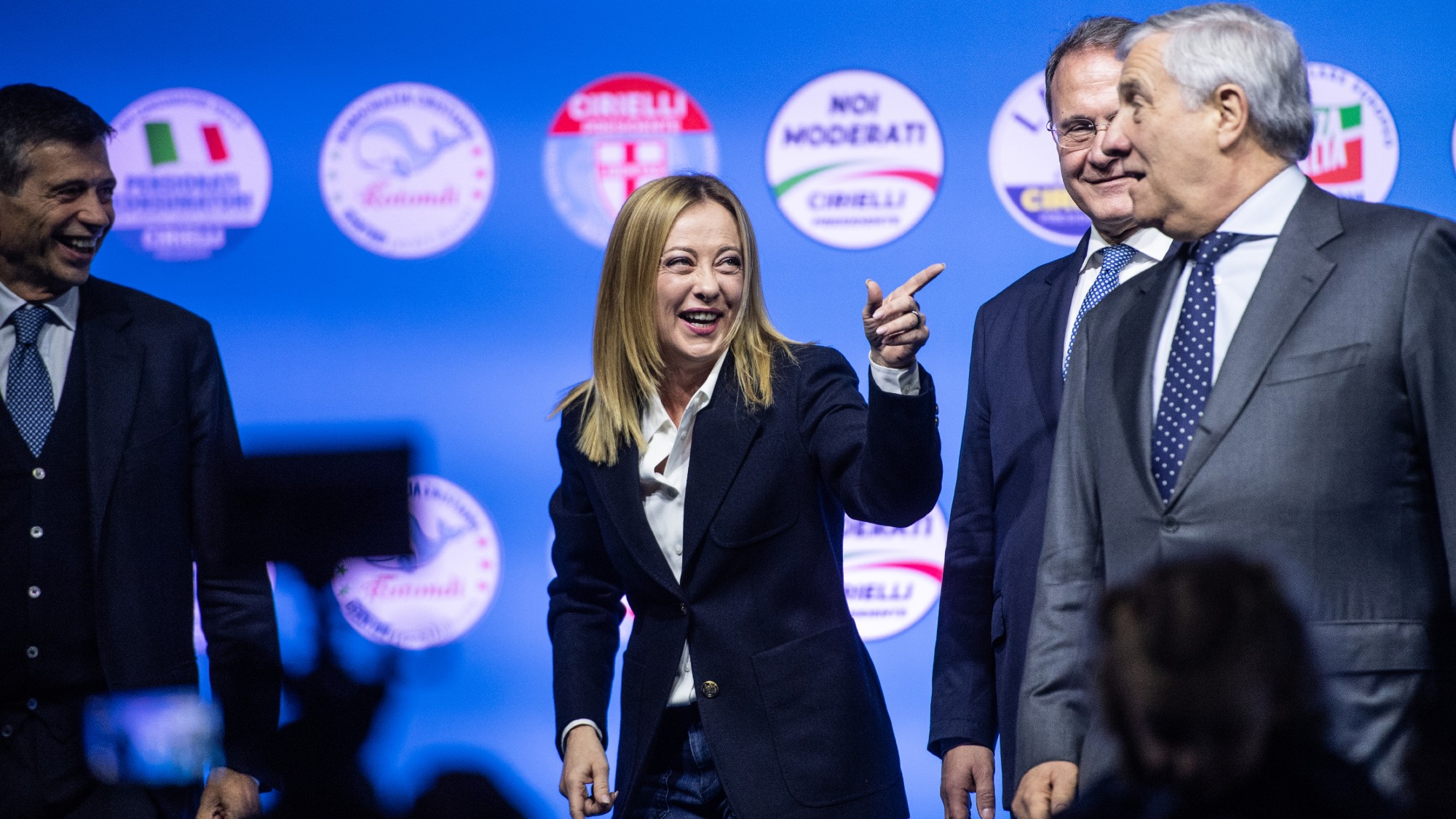 Giorgia Meloni laughs and points on stage at an election rally in Naples 