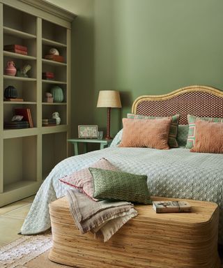 Green bedroom with rattan bed decor and quilted throw