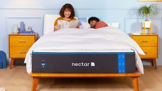 best mattress: Nectar Memory Foam Mattress on a wooden bed base in a colourful room, with a couple sat up in bed