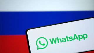 Smartphone displaying WhatsApp logo in front of Russian flag