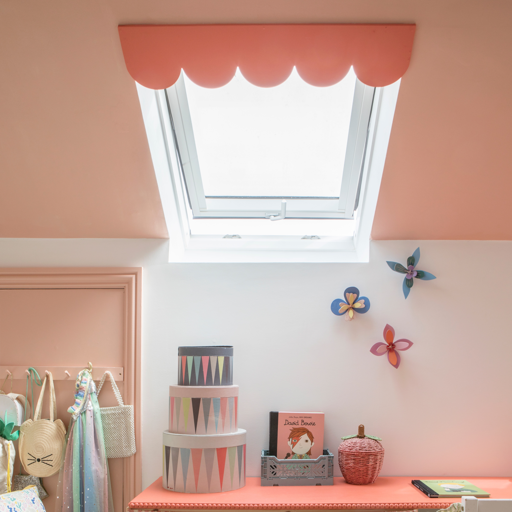 a child's room with a pink painted ceiling, a Velux window and a scalloped pelmet