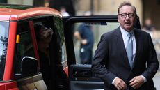 Kevin Spacey, wearing a suit, beside a car