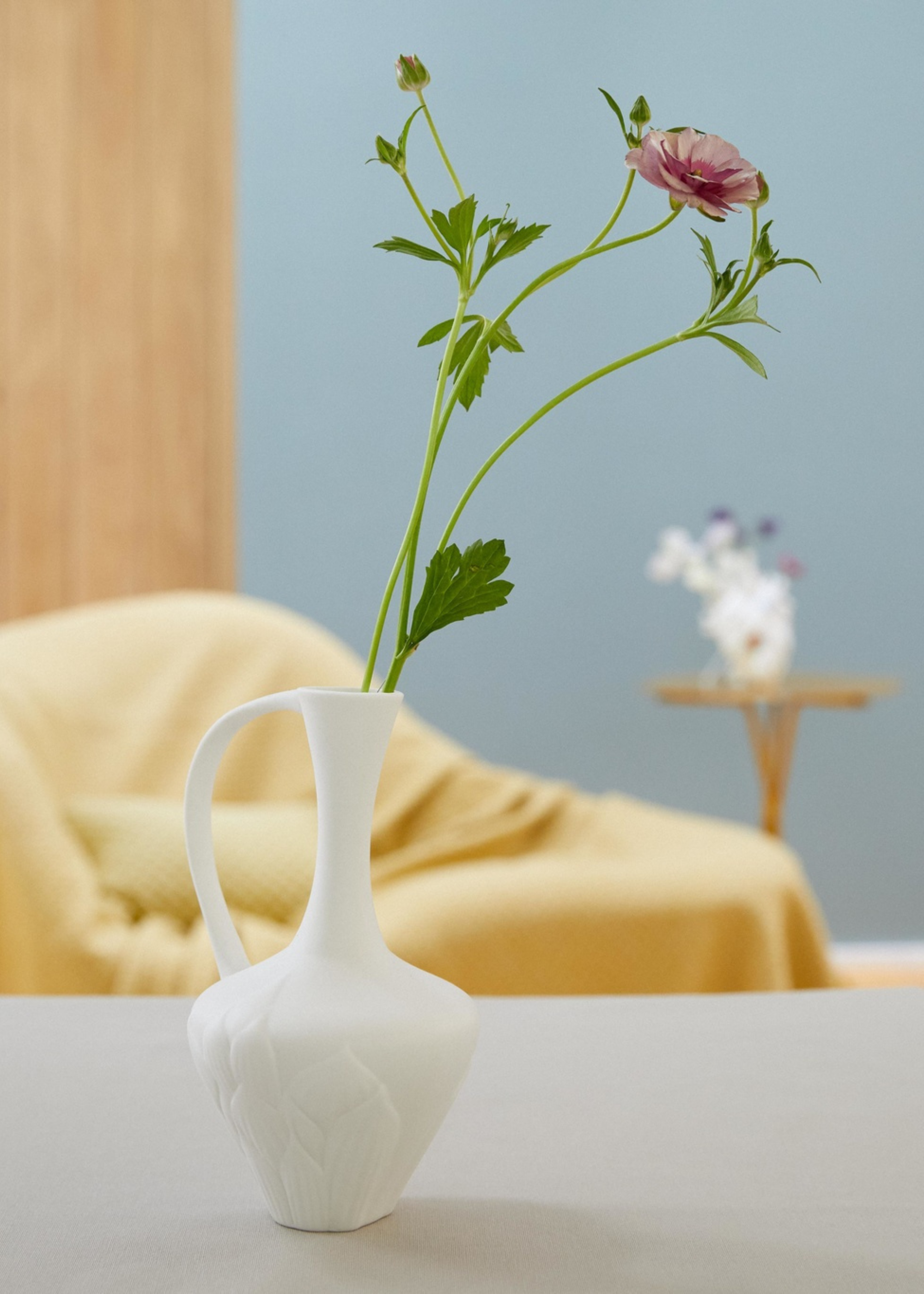 A vase with a purple sweet pea flower