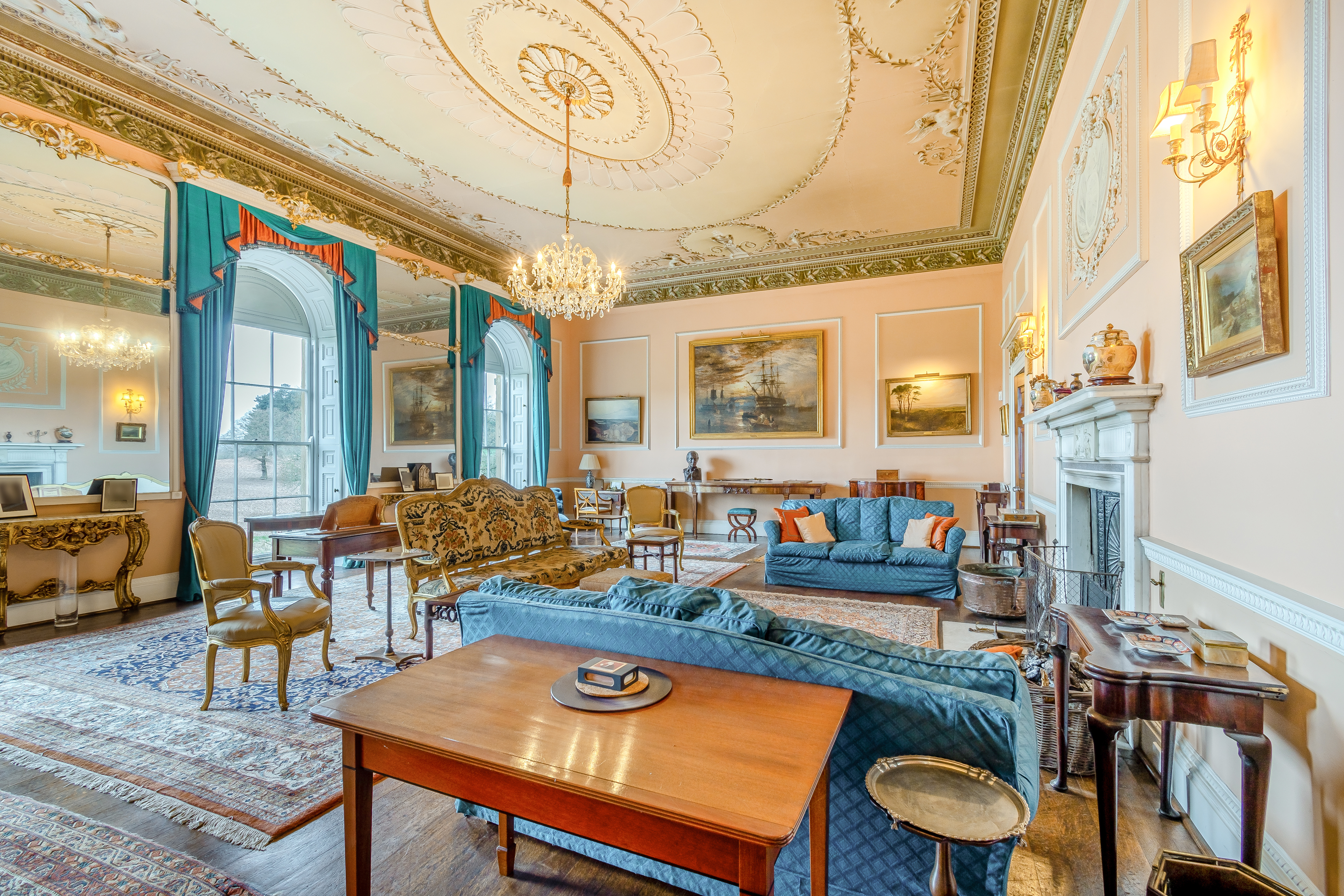 Inside a living room with teal sofas, gilded chairs and a chandelier