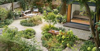 Beautifully landscaped garden with paving and circular flower beds and water feature to show sensory garden ideas