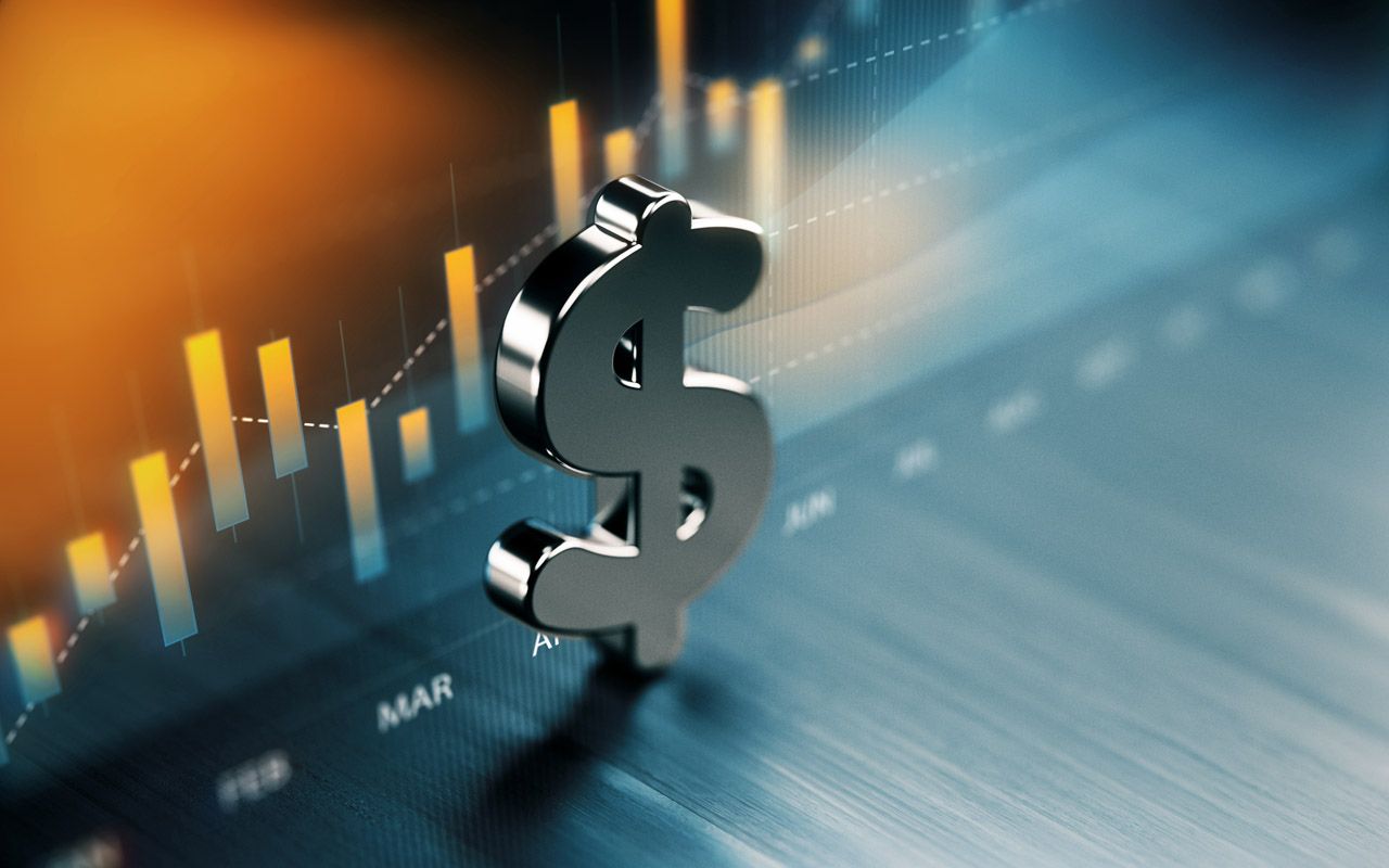 American dollar symbol standing on wood surface in front of a graph. Selective focus. Horizontal composition with copy space.