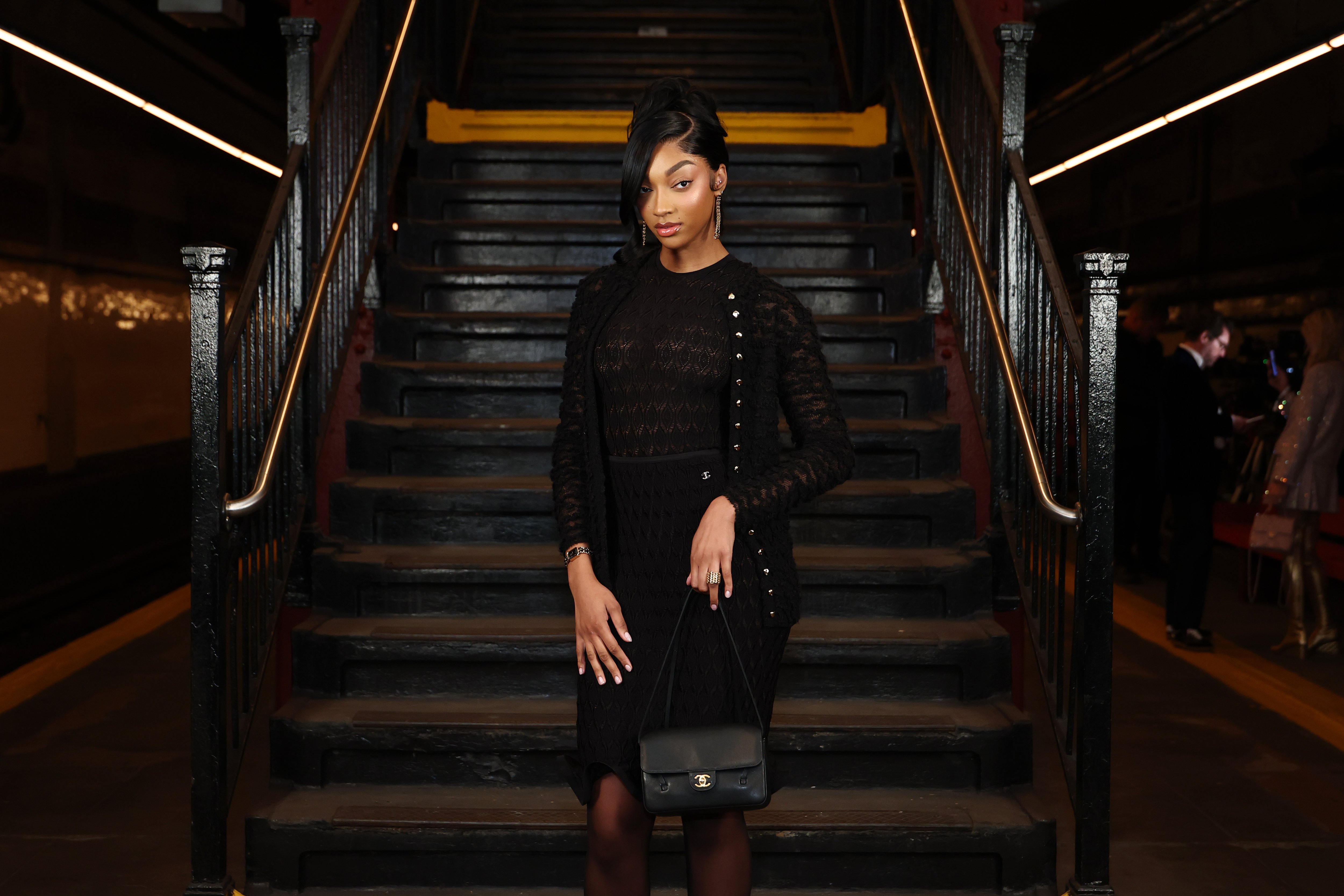 Angel Reese wearing a French twist hairstyle and black lace skirt set