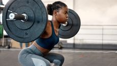 Woman doing squats at gym with barbell
