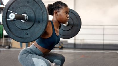 Woman doing squats at gym with barbell