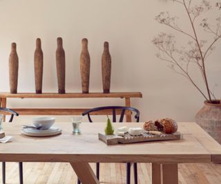 The dining nook of a kitchen with a wooden table, wooden chairs and wooden decor pieces.