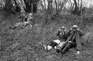 Two couples sat by a fence and staring through binoculars