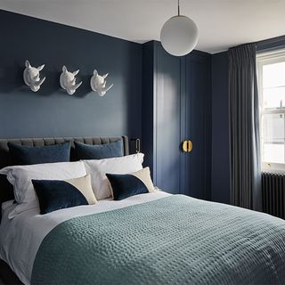 dark blue bedroom with dark blue cupboard bed with designed cushions