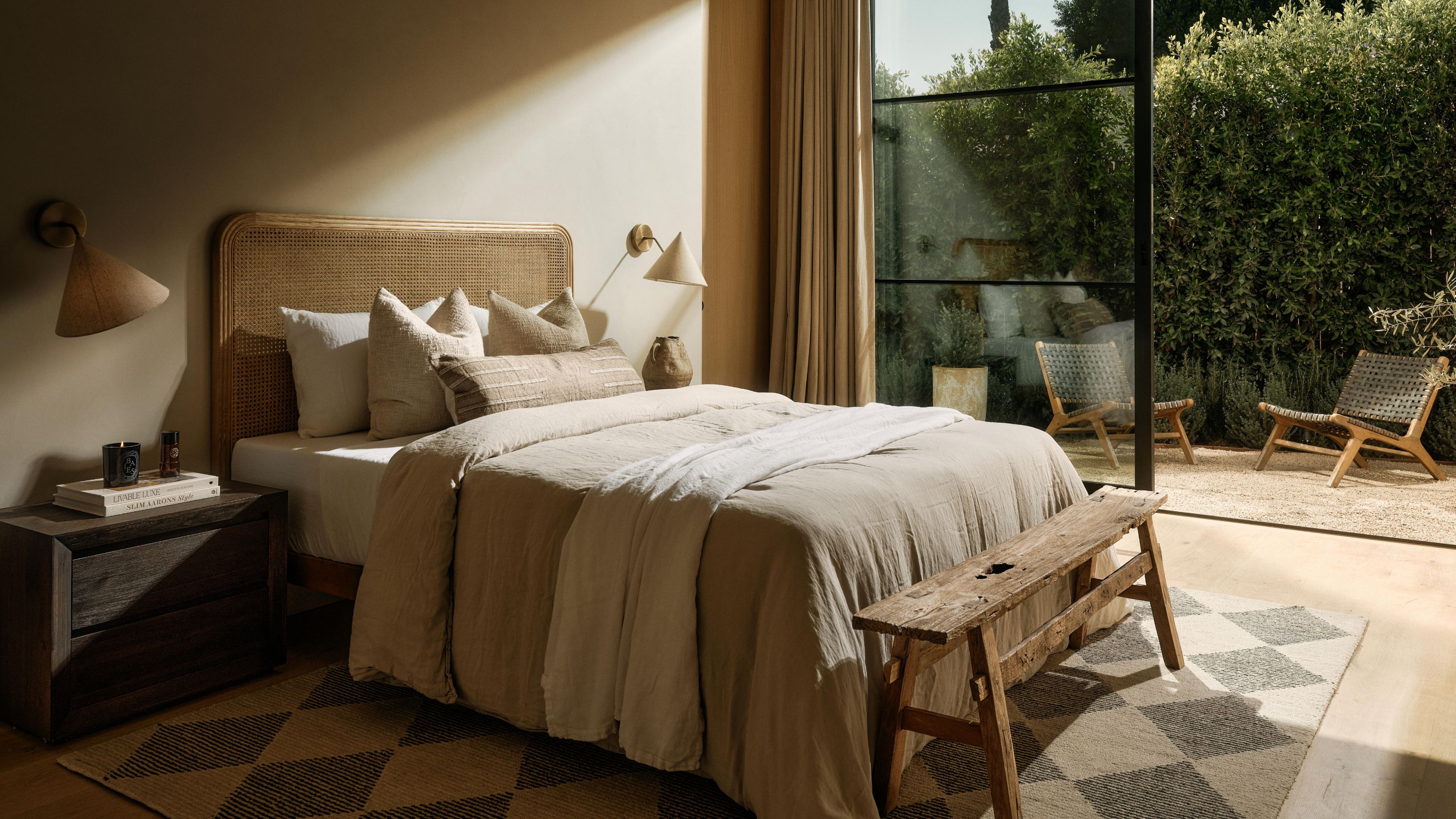 a modern organic bedroom with checkered rug, rattan and wooden decor and a private terrace