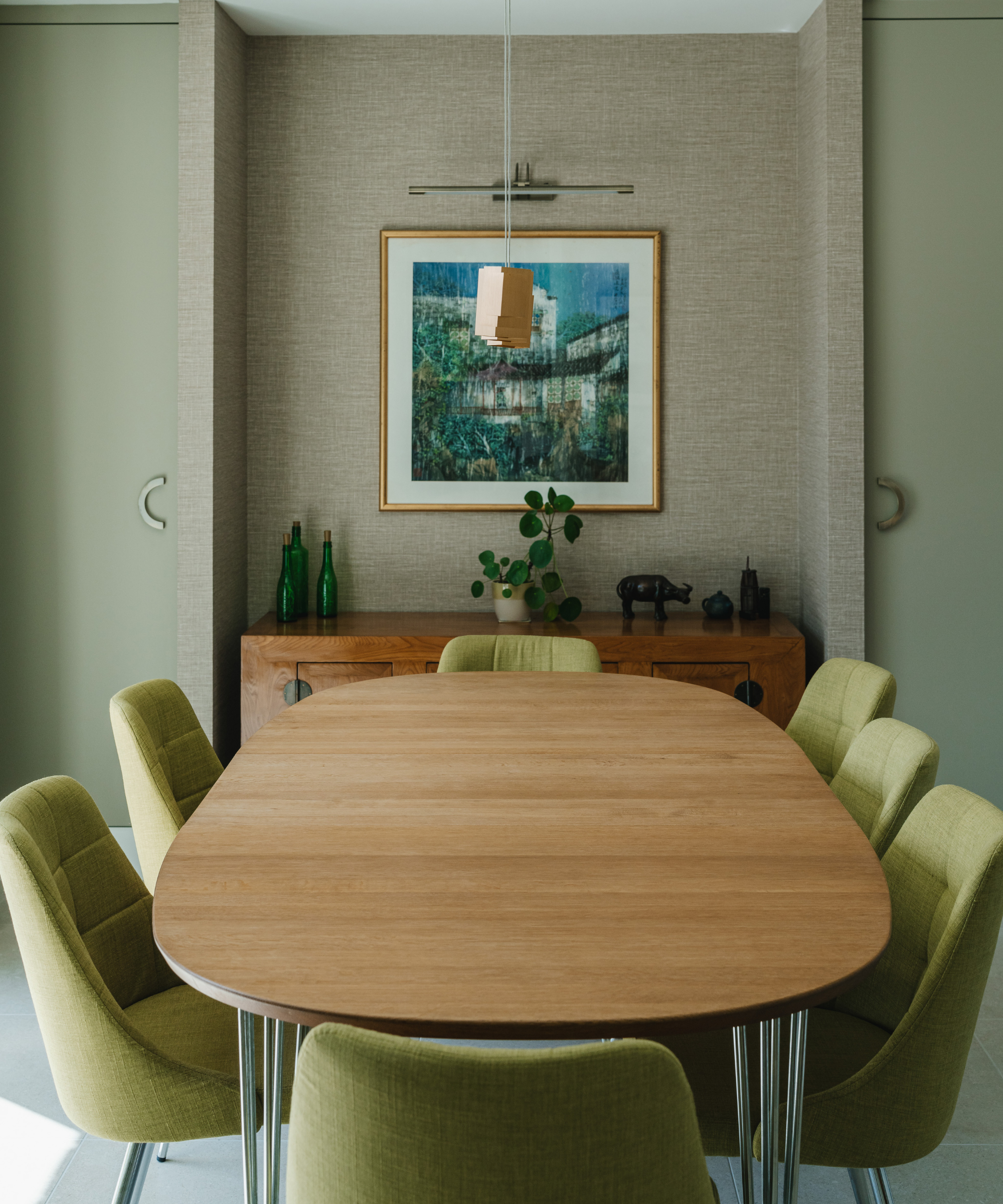 Dining room with green chairs, green wall, wooden table and wooden cabinet behind