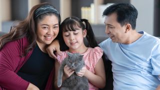 Happy family sat on couch with their cat