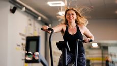 A smiling woman exercising on a cross-trainer at home