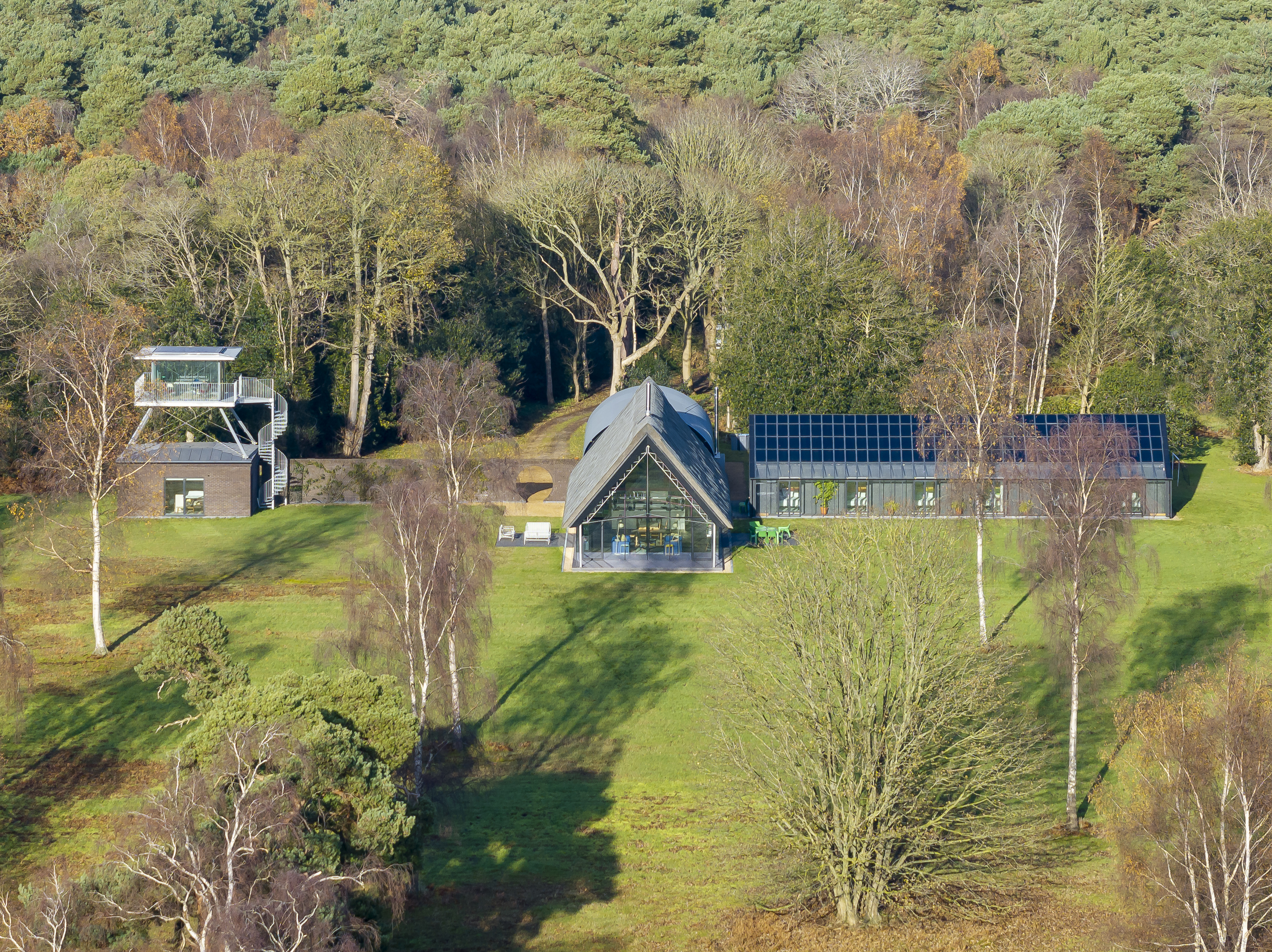 homestead as seen from the air, a cruciform experimental UK home among leafy countryside