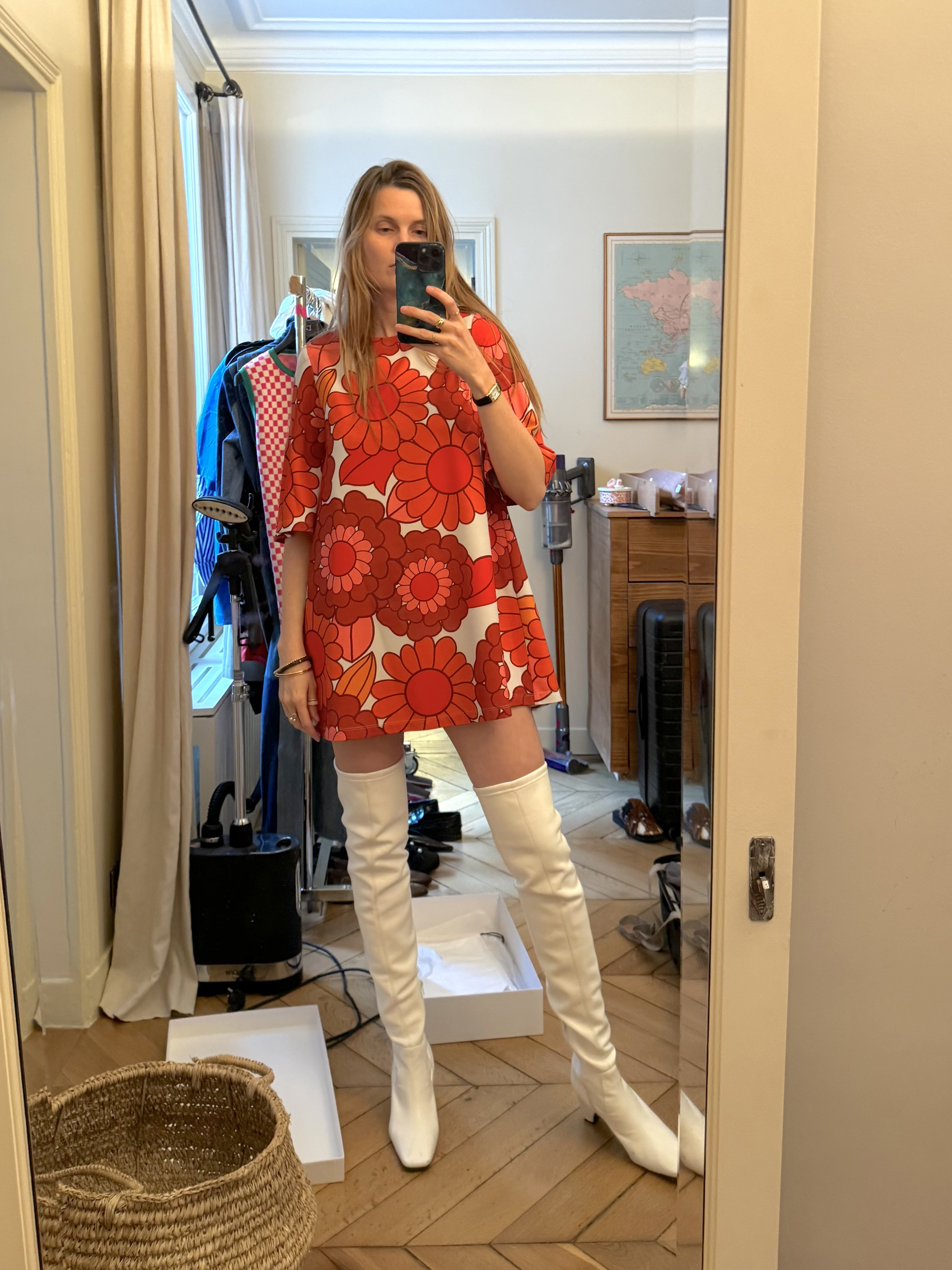 French editor Eugenie Trochu poses for a mirror selfie wearing a flower-print shift mini dress and thigh-high white boots